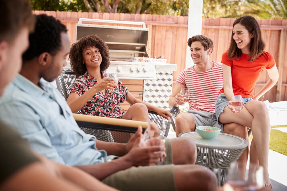 Young adult friends relaxing on the porch outside a house