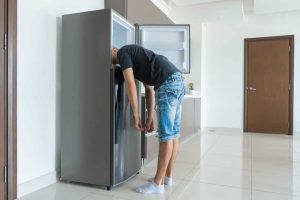 On a hot day, the guy cools with his head in the refrigerator. Broken air conditioner.