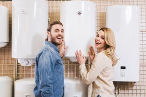 smiling boyfriend and girlfriend deciding between hot water heater or boiler in home appliance store