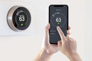 A person using a smart phone application saving energy with a smart thermostat