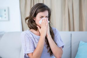 woman with allergies blowing her nose